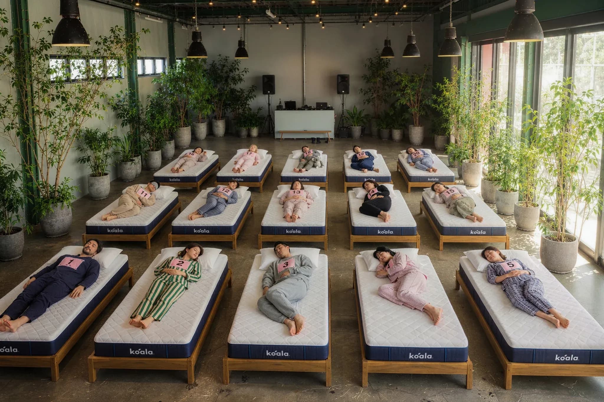 Participants lie on Koala mattresses arranged in neat rows inside a bright, plant‑filled venue during Matt Race by Koala in Tokyo.