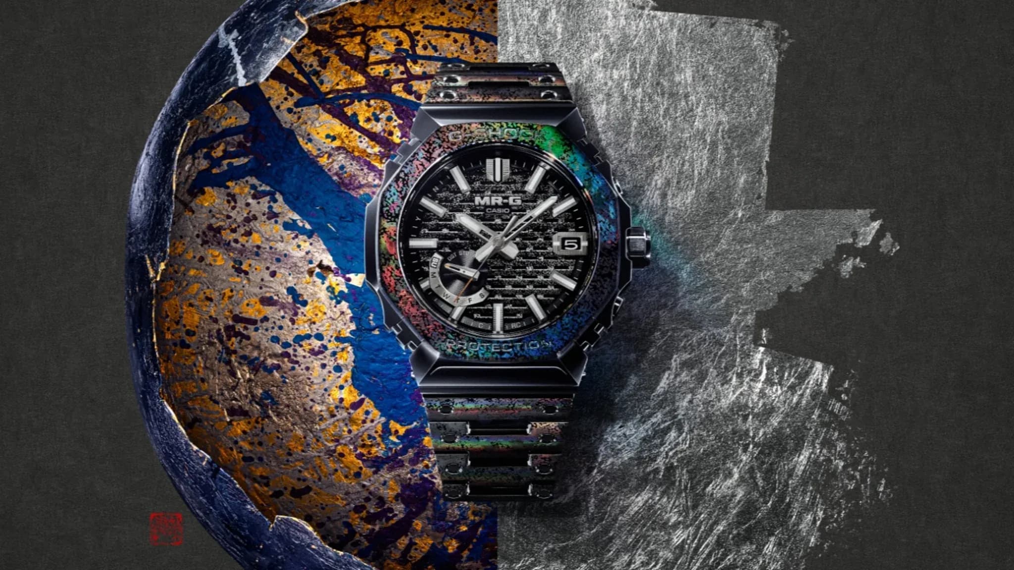 Close‑up of Casio’s MRG‑B2100HR‑1A watch showing its iridescent bezel and intricate dial against a textured metallic background.
